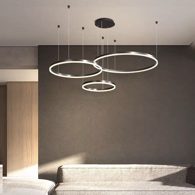 Lustra LED inele circulare montata in living modern, atmosfera calda, suspendata la inaltimi diferite
