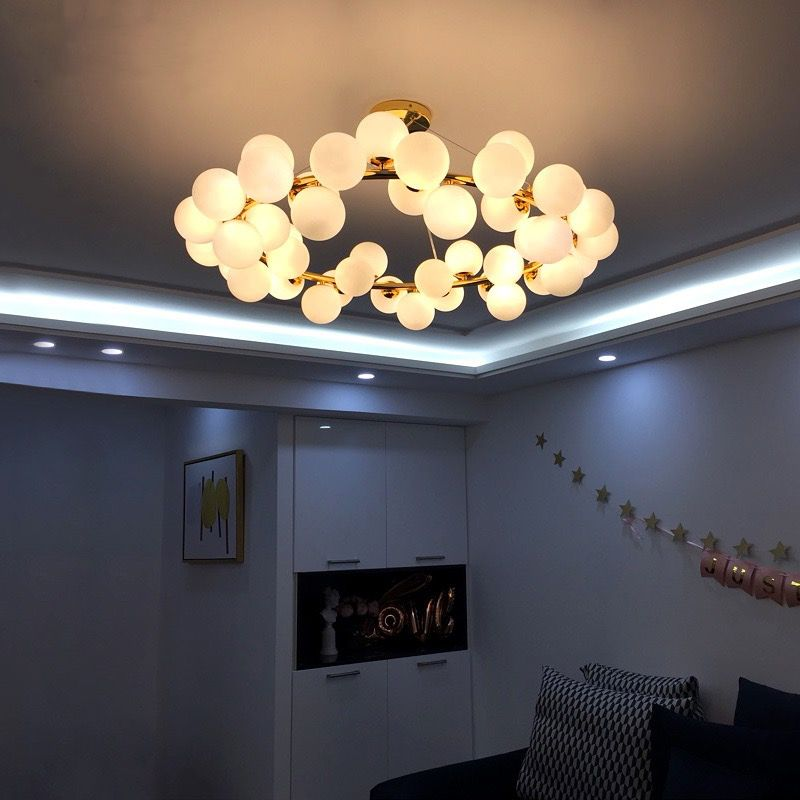 Lustra cu globuri montata pe tavan in living modern, efect decorativ auriu vizibil in spatiu real