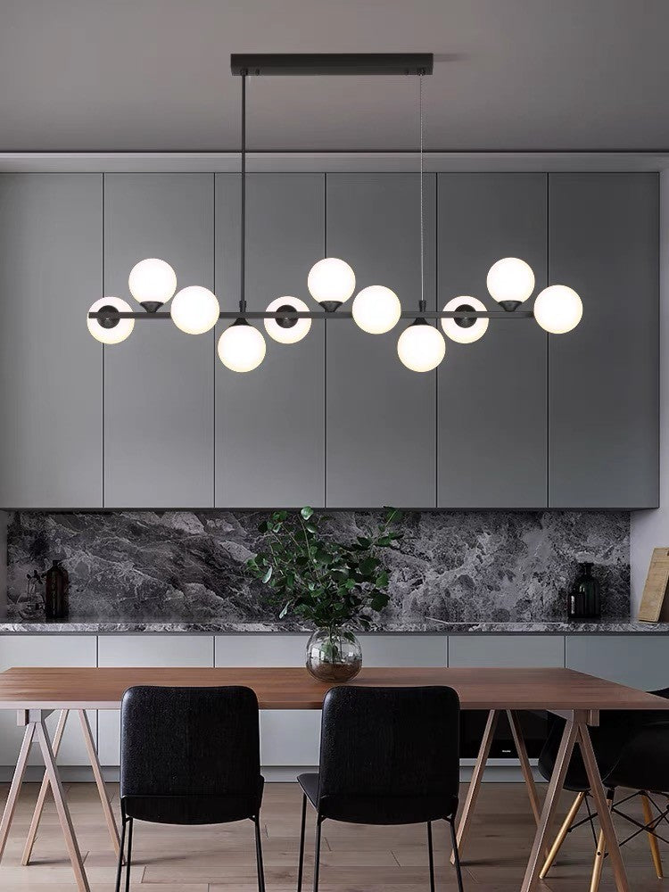 Lustra liniara cu globuri albe mate in varianta neagra, suspendata deasupra mesei de dining modern