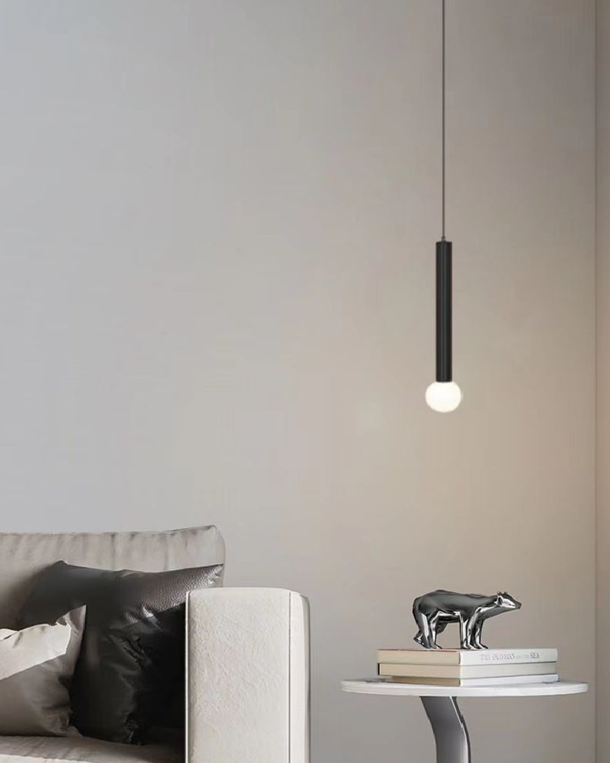 Lustra LED pe cablu neagra cu glob opal aprins, montata deasupra noptiere in living