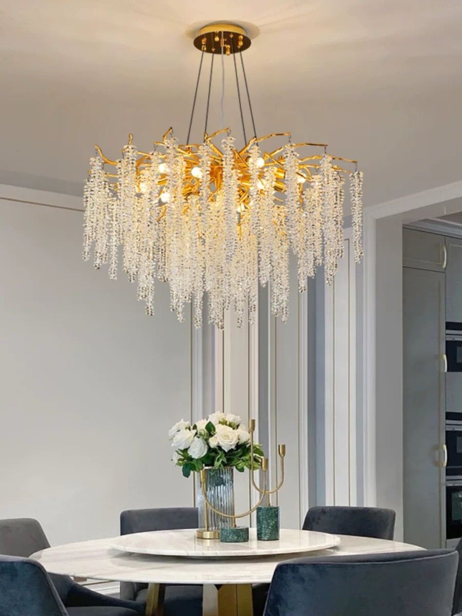 Candelabru cristal auriu cu siraguri cascada, montat deasupra mesei de dining rotunde, aspect elegant