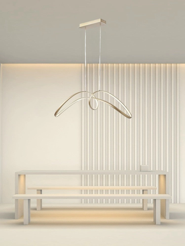 Lustra LED aurie cu design sculptural montata deasupra unei mese, aspect in interior minimalist contemporan
