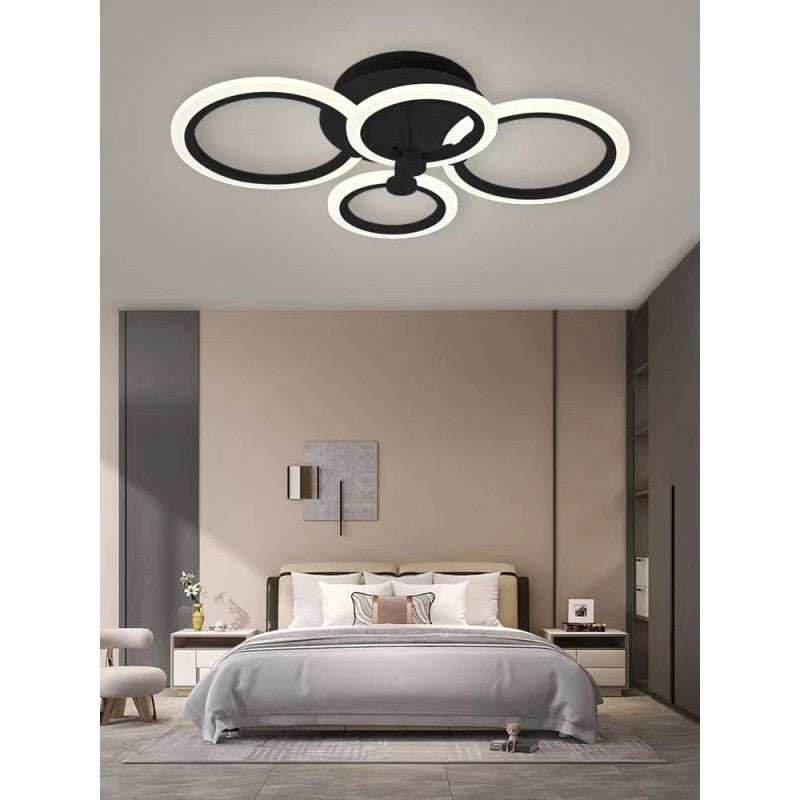 Plafoniera LED cu 4 cercuri negre pe tavan, aspect decorativ in dormitor luminos