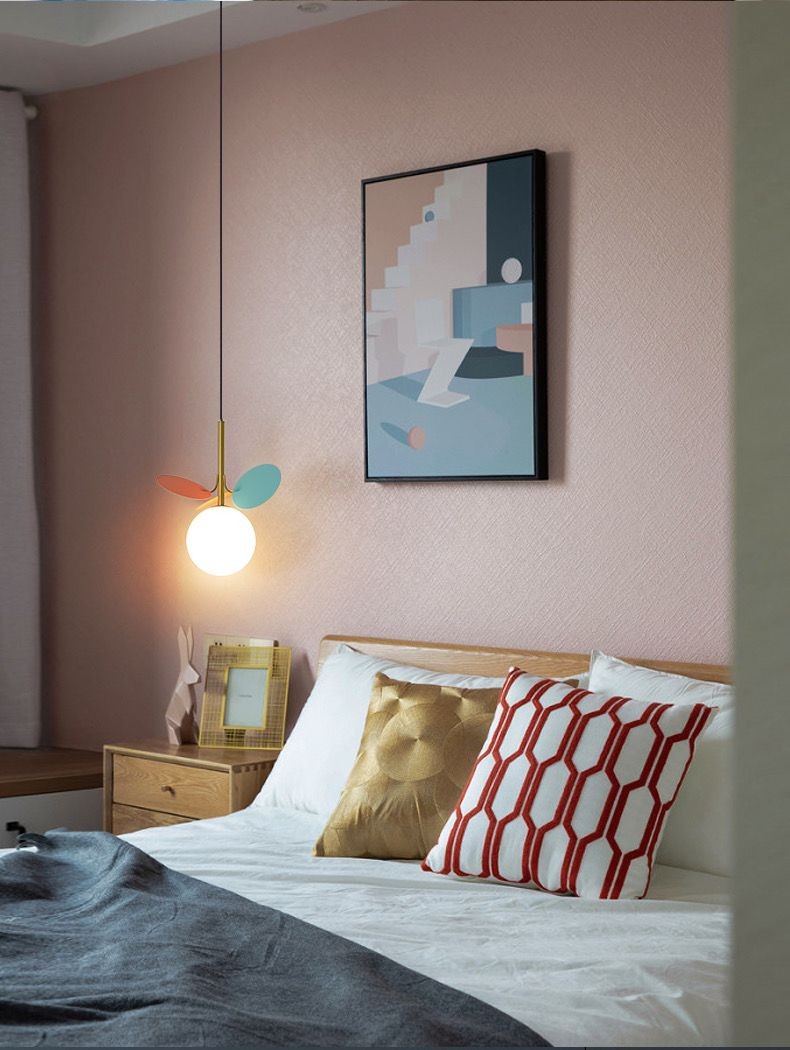 Lustra suspendata cu discuri colorate pastelate si glob opalescent, integrata in decorul unui dormitor modern