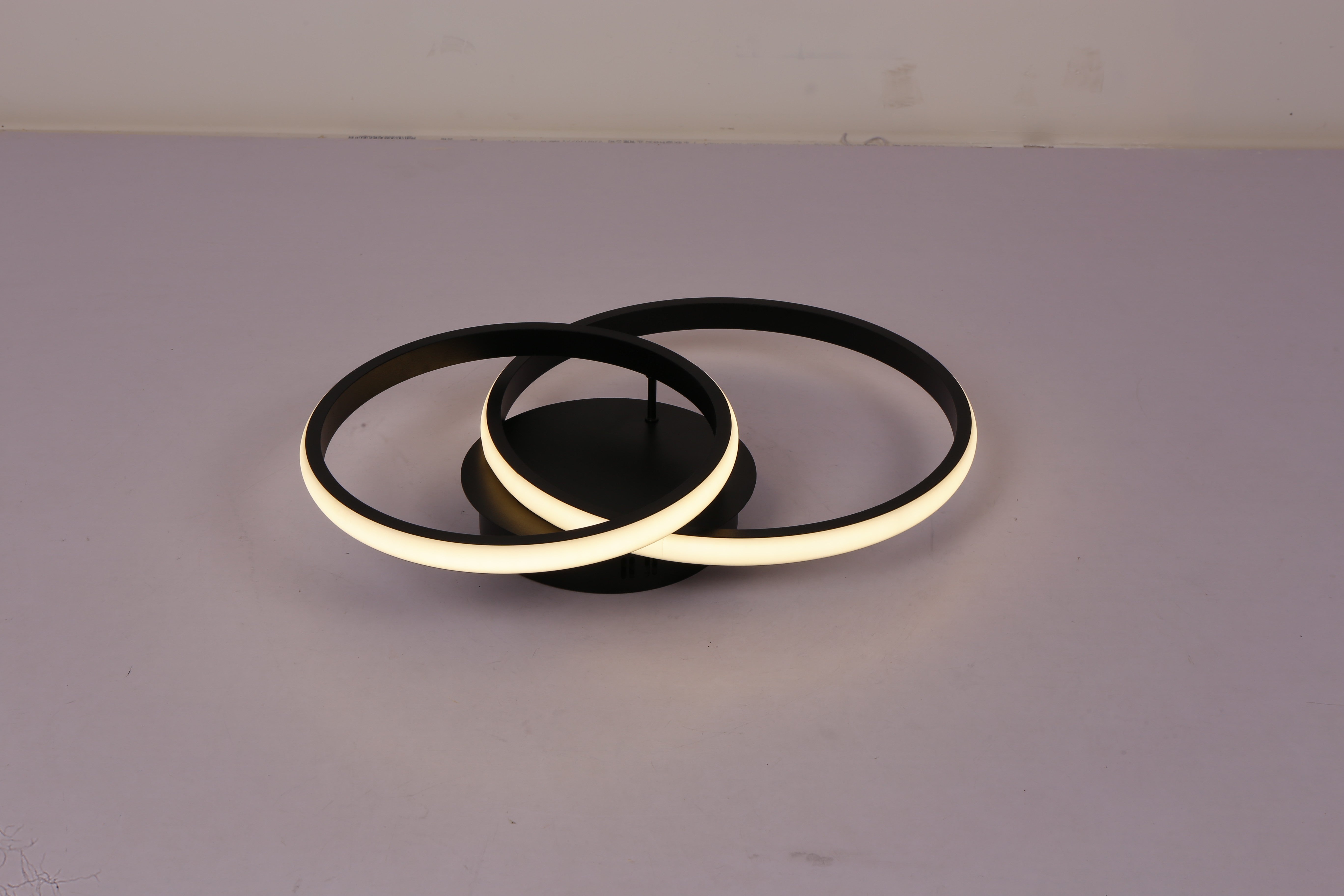 Plafoniera LED doua inele negre aprinsa, lumina calda intensa, vedere de sus pe fond gri